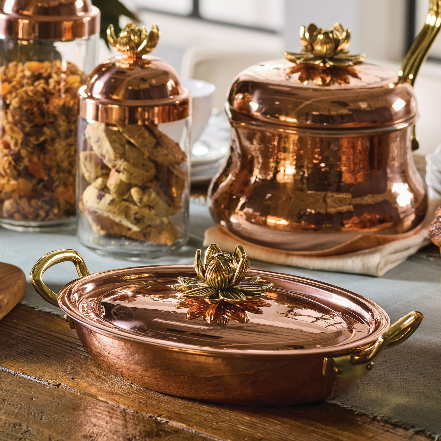 Hammered copper 10" covered oval gratin, tin-lined by hand over fire, with bronze handles. Shown with matching tea kettle and Lotus glass jars from the Glamstore Historia collection