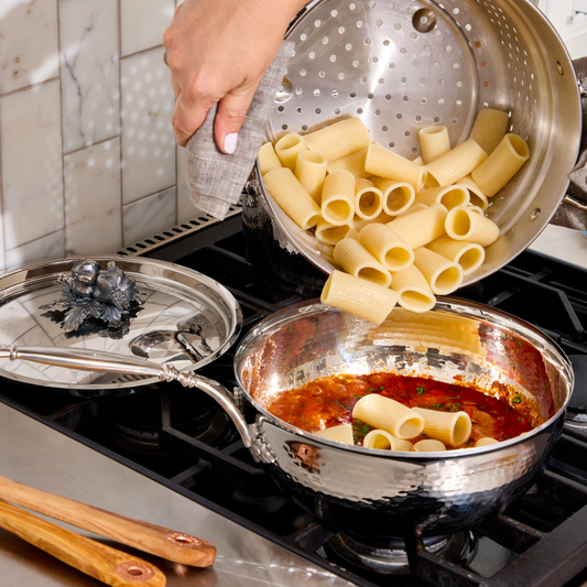 Tomato tuna sauce pasta with rigatoni in an Opus Prima hammered-clad stainless steel chef's pan decorated silver-plated lid knob finial.