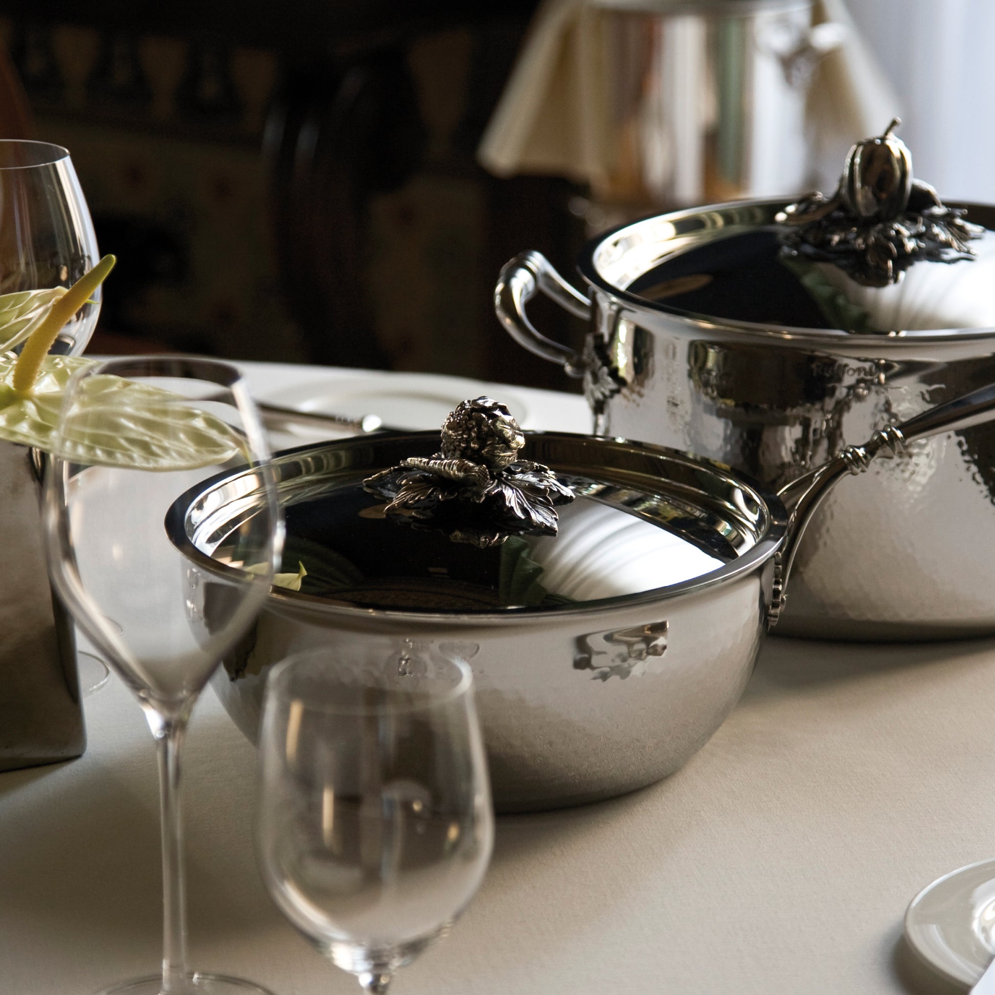 Opus Prima hammered clad stainless steel chef pan and stockpot with decorated silver-plated lid knob finial  on a classic tablesetting