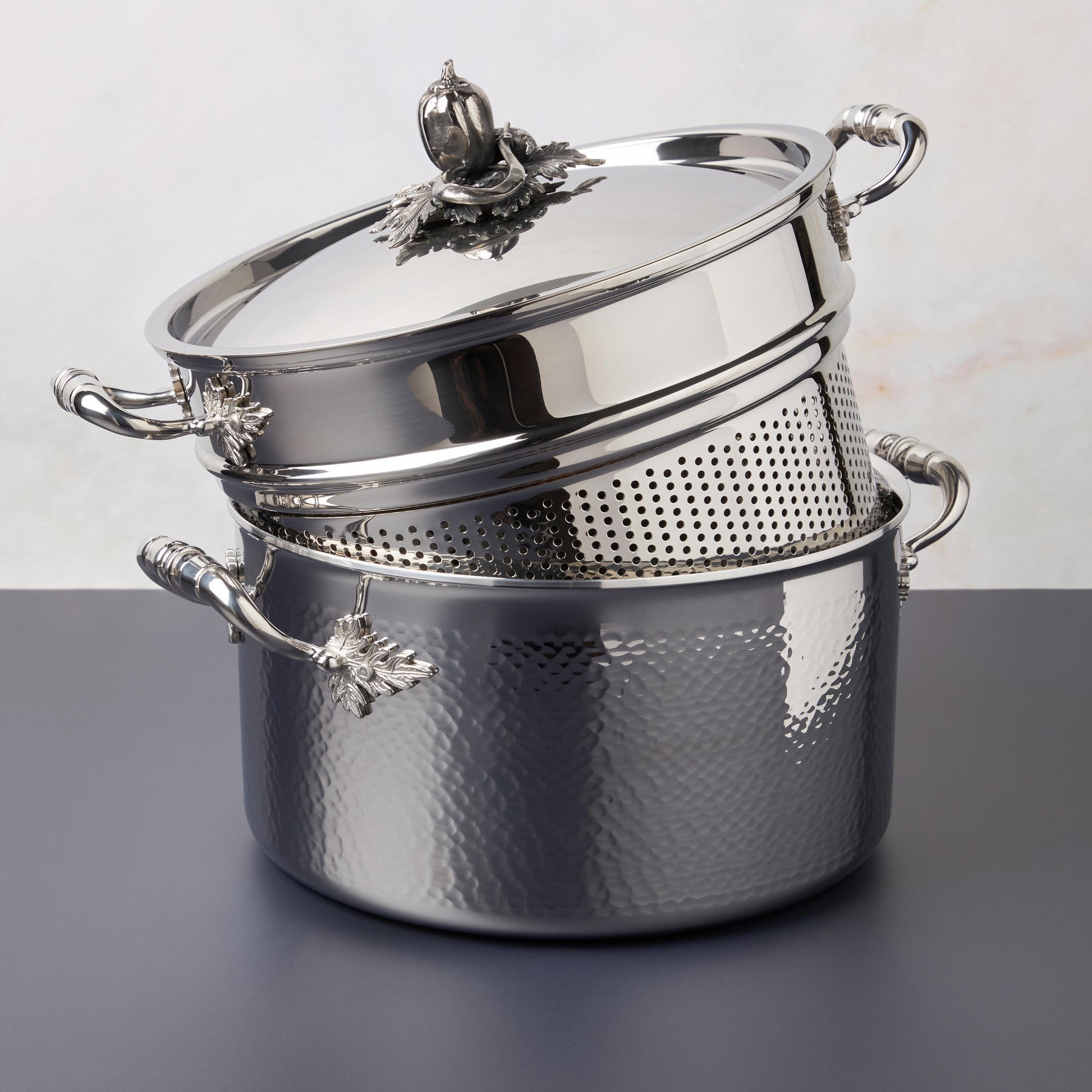 Opus Prima hammered clad stainless steel stockpot with decorated silver-plated lid knob finial  photographed with the matching pasta insert