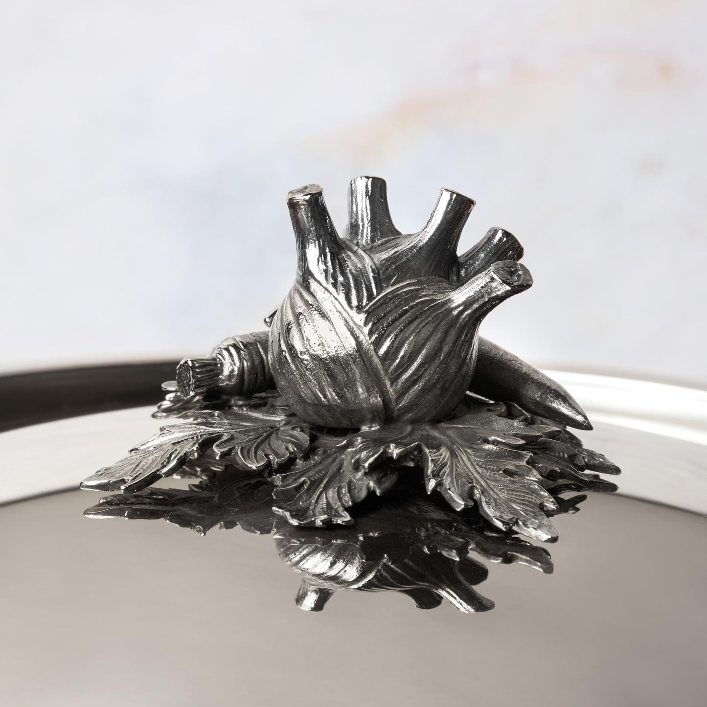 Decorated knob finial representing fennel, carrot and bean, cast in solid bronze and silver plated, on Opus Prima stainless steel lid