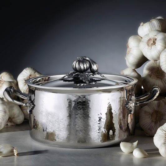 Opus Prima hammered clad stainless steel soup pot with decorated silver-plated lid knob finial on a garlic background