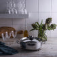 Opus Prima hammered clad stainless steel braiser with decorated silver-plated lid knob finial  an Italian kitchen with glass and artichokes