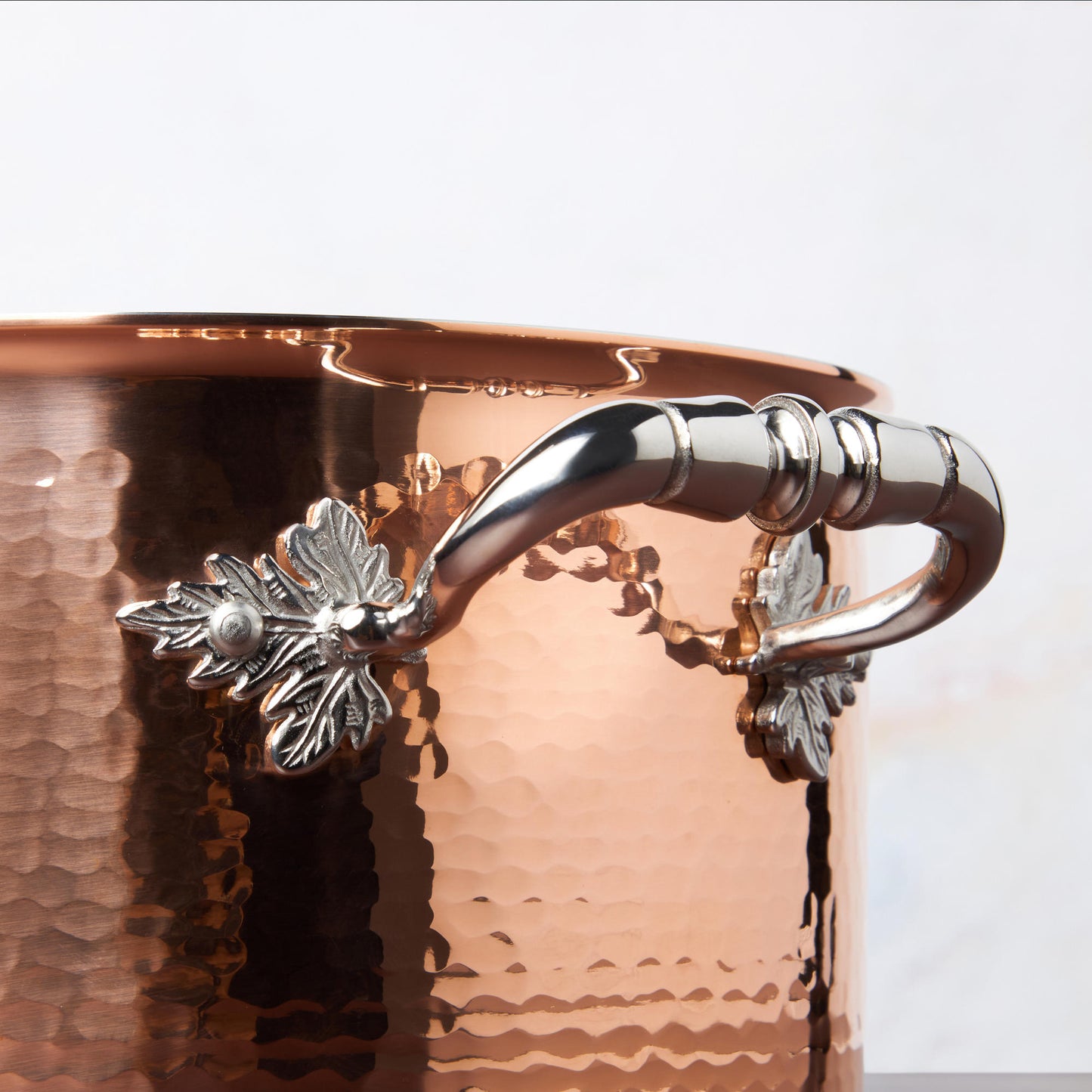 Beautiful stainless steel helper handle decorated with delicate leaves on Opus Cupra cookware