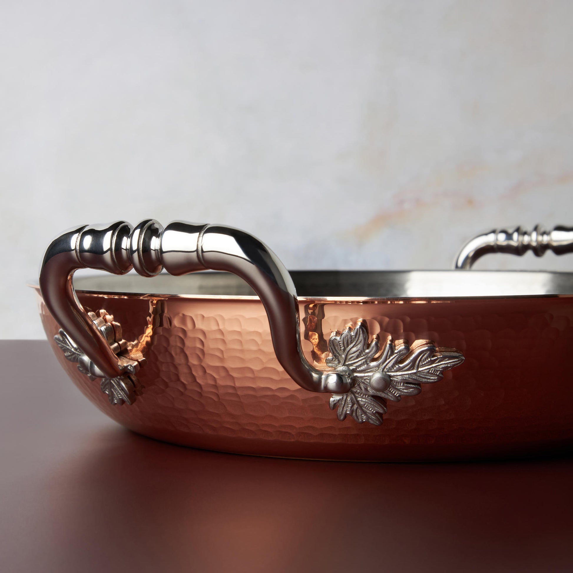 Beautiful stainless steel handle decorated with delicate leaves on Opus Cupra cookware