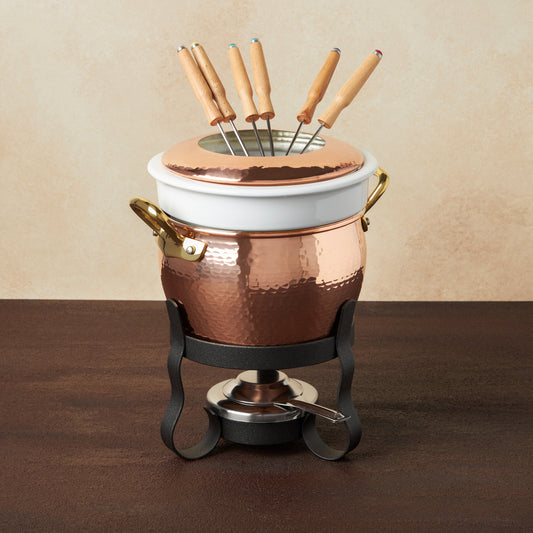 Hammered copper 11 Piece Fondue Michelle Set lined with high purity tin applied by hand over fire and bronze handles, from Glamstore Historia collection. The full set includes: tin-lined copper fondue pot, porcelain insert, decorative wrought iron stand, gel fuel holder, and six fondue forks.