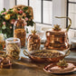 lotus 5 piece set including a copper tea kettle, copper 10" roaster and a set of 3 kitchen glass jars in glass and copper, all topped by lotus-shaped bronze knobs